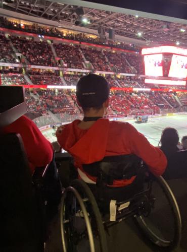 Kingsley watches the World Juniors Game from his wheelchair surrounded by fans in red