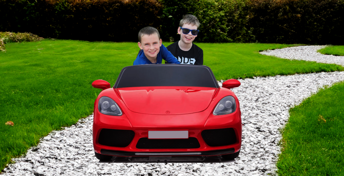 Logan outdoors riding in his red Porsche ride-on car